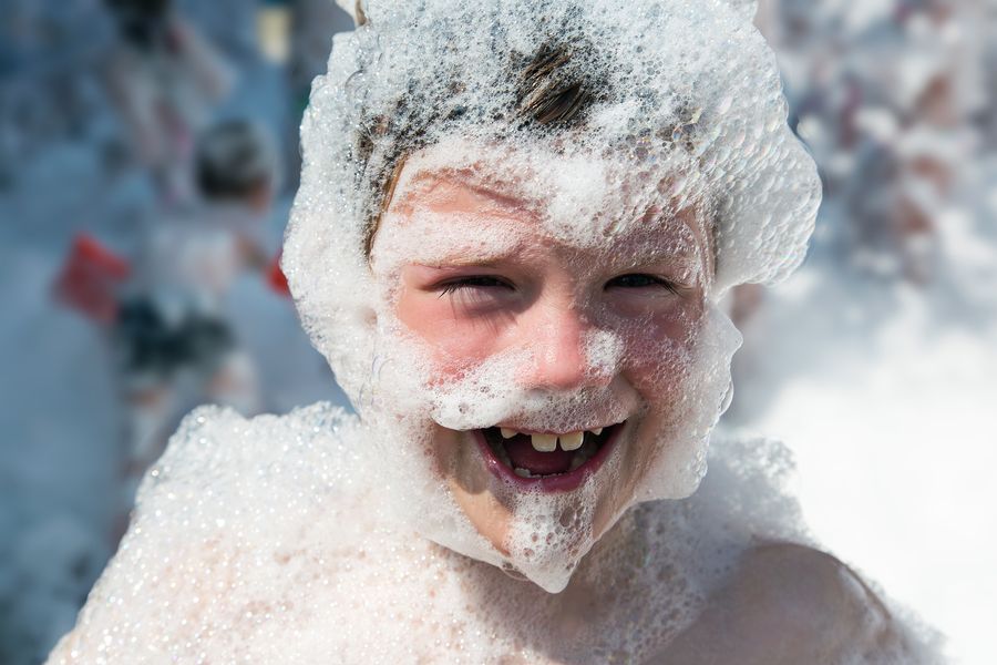 Group of kids jumping and celebrating in foam outdoors